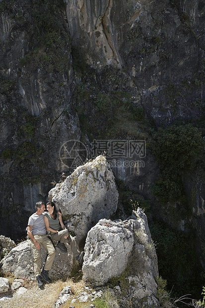 坐在山边的岩石上 对一对轻松的情侣旅游女士成人孤独团结冒险边缘沉思假期闲暇图片