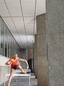 妇女在建筑物外跳跃障碍运动服装场景跑步头发女士田径成人中年人中年图片