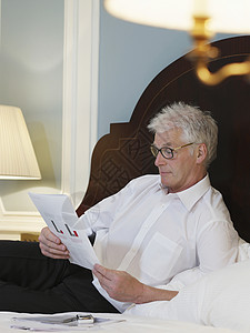 中年男子在床上阅读文件图片