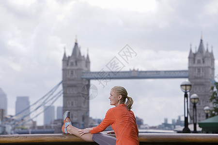 妇女伸展在大塔桥前 在英国伦敦成人马尾辫头发微笑休闲服装中年女士位置一人图片