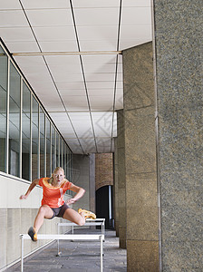 妇女在建筑物外跳跃障碍成年女性建筑外观中年场景女士运动摄影头发图片