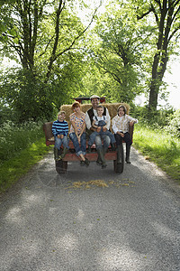 有三个子女的父母59个子女坐在国家车道上的拖车上父亲男人幸福成人孩子干草风景拥抱享受风光图片