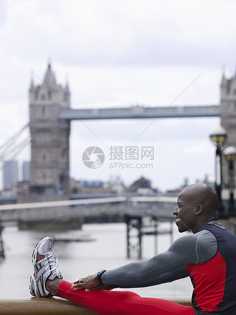 一位非洲裔美国人的侧视景 在英格兰塔桥前伸展一面运动员双手男人城市闲暇运动肌肉娱乐活力建筑学图片
