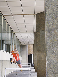 妇女在建筑物外跳跃障碍中年人成年成人场景田径头发一人女士跑步服装图片