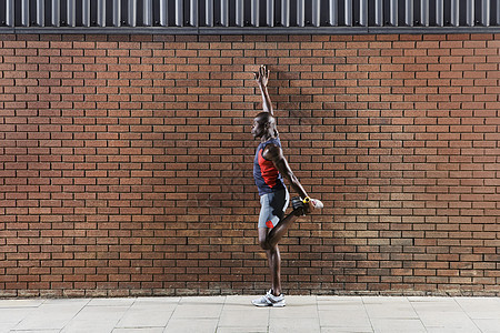 一个非裔美国人 站在砖墙的侧面全长的一面观图片
