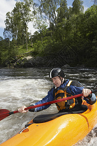 年轻男子在河里划皮艇的景象白水夹克危险橙子享受运动爱好行动挑战娱乐图片