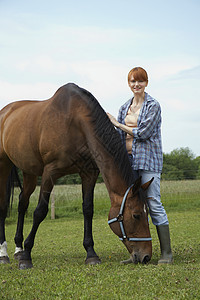 一个微笑着的女人的全长肖像 田里有马匹草地宠物友谊农场成人衬衫农田女士牛仔裤动物图片
