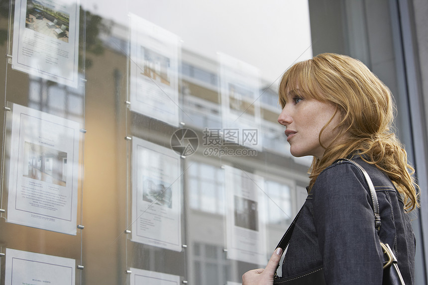 一位年轻女性观看房地产办公室窗口展露的侧面视景图片