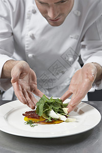 在厨房里做沙拉的男厨师商业晚餐专注男性食物准备裁剪绿色双手服务图片