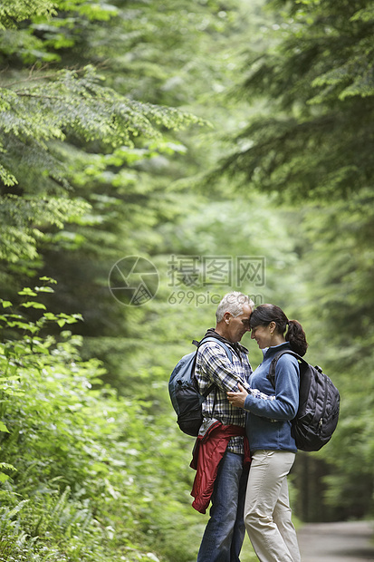 一对中年夫妇拥抱森林道路的侧面观点图片