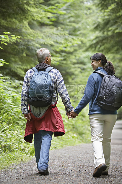 沿森林道路后视线行走的夫妇图片