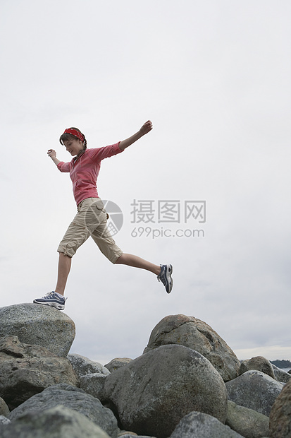 手伸展的女人 在岩石上跳跃图片