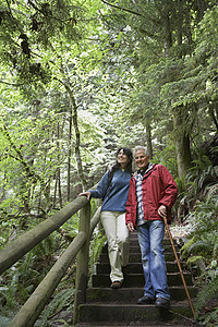 在森林足迹上行走的老年男子和中年妇女图片
