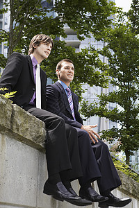 办公室外墙上两名青年商务人士的低角度视角 视角较低背景图片