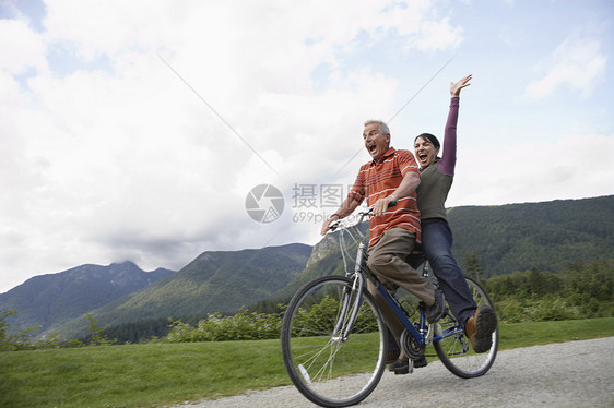 在乡村公路上骑自行车的中年夫妇喜悦的中年夫妇的低角度视角图片