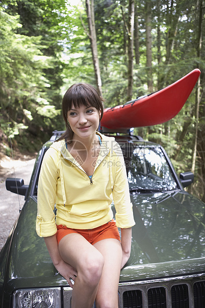 在森林里坐在汽车帽上的女人图片