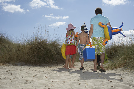 父母和三名子女在岸上携带海滩附件的全长后方视线图片