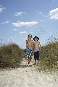 两名男孩用渔网在沙沙沙丘上行走的完整肖像图片