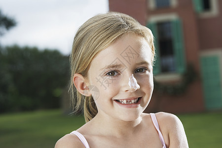 一个笑着可爱女孩的近镜肖像 鼻子上涂了防晒霜图片
