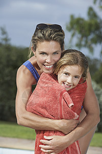 微笑的母亲的肖像 她拥抱着用毛巾包着的女儿图片