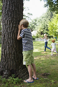 男孩站在树上 眼睛像儿童在幕后奔跑一样被蒙着眼睛图片