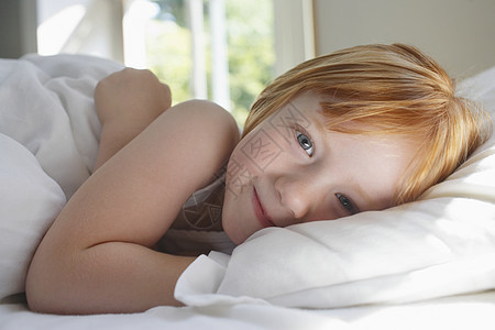 在家床上躺着的可爱小女孩的肖像图片