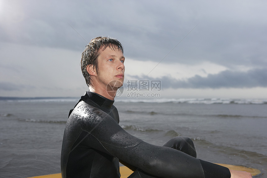 在水边视图中坐着冲浪板的Surfer图片