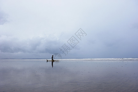 孤单冲浪者坐在浅水边风景的冲浪板上图片