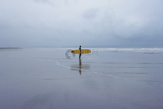 孤单冲浪者站在浅水边的浅水景图片