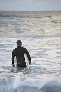男性冲浪者携带冲浪船入海的近视图片