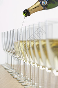 装满一排玻璃杯的香槟瓶 有选择性地聚焦背景图片