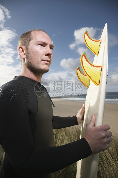 男性冲浪者在海滩上携带冲浪板的侧面景色图片