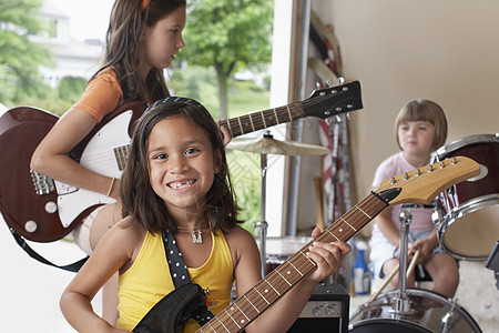 快乐的年轻女孩在车库里弹吉他和乐队的肖像图片