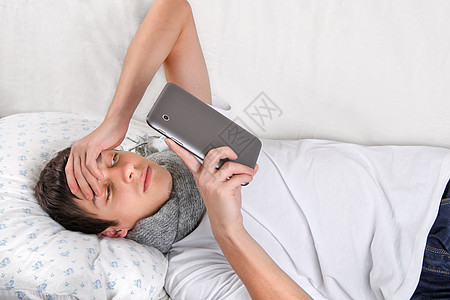 配有平板电脑的年轻人阅读沙发流感药片工具男性围巾互联网说谎枕头图片