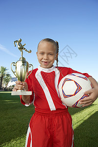 持有战利奖杯和田野足球球的年轻女孩肖像图片