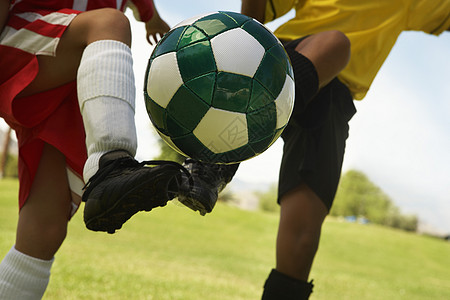 两名多族裔足球运动员踢足球球的中区图片