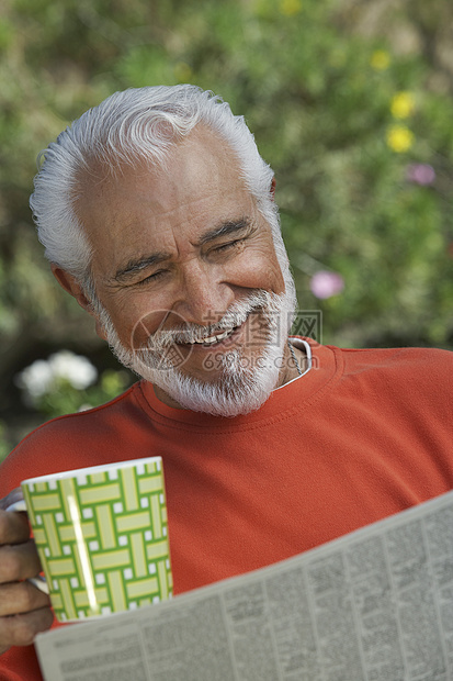 快乐的老人看报纸 当他喝咖啡杯的时候图片