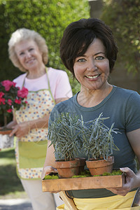 一位快乐的女子的肖像 她拿着盆栽植物 母亲站在幕后站立着图片