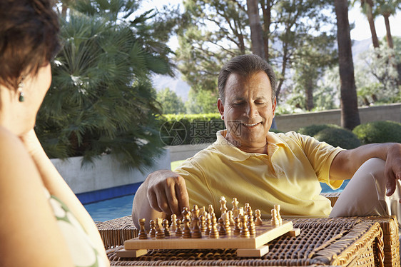 快乐的一对夫妇在游泳池下象棋图片