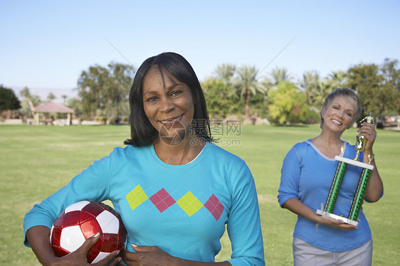 在公园肖像中拥有足球球和奖杯的资深妇女图片