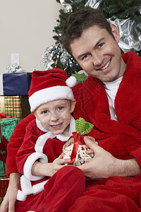 带着圣诞礼物的白种父亲和儿子 在圣诞圣诞老人服装中的肖像图片