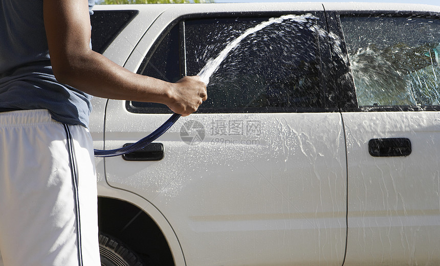 男子用水管喷洒汽车的中流体图片