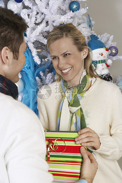 在圣诞树前从一个男人那里得到礼物的快乐女性图片