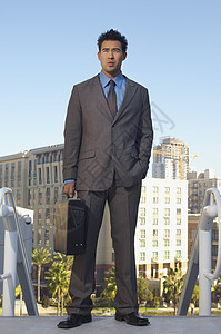一个自信的商务人士的全长 背着公文包 背景是建筑物图片