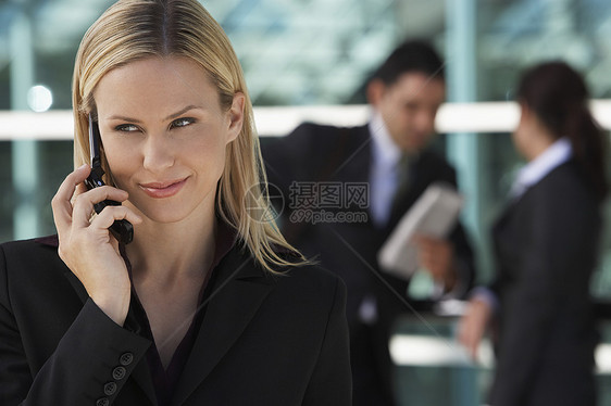 与背景同事使用手机的漂亮商业女商务人士AC 1女性头发细胞中年人士长发电话女士肩膀中年人图片