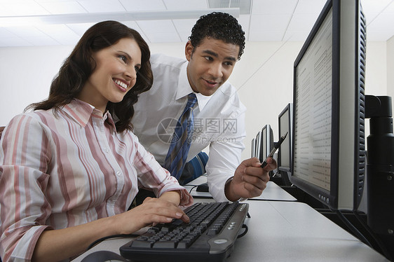 商务人士指向屏幕 而妇女则在键盘上打字图片
