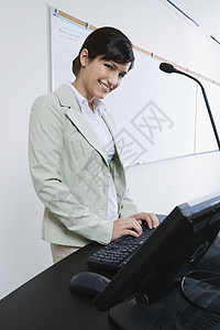 一位在课堂上使用计算机 微笑着的女讲师的肖像图片