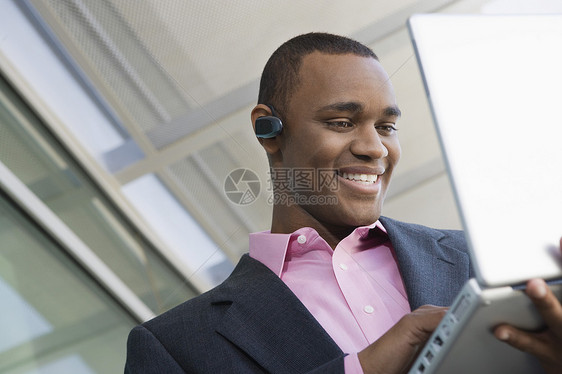 从事笔记本电脑工作的非裔美国商务人士中年人黑发西装短发耳机幸福黑人肩膀享受男人图片