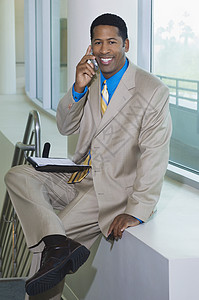 一位快乐的非裔美国商务人士在召回时的肖像电话中年人男子黑人商业露齿细胞双腿享受中年图片