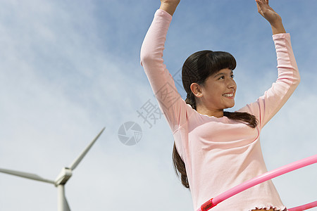 在风力农场玩呼啦圈的快乐女孩图片